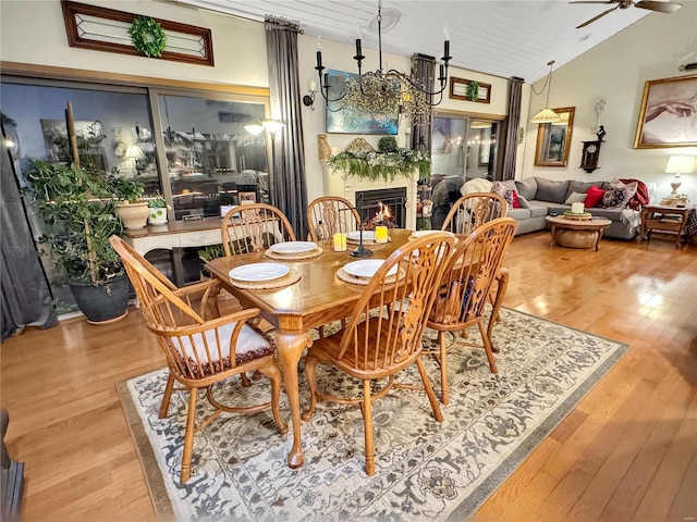 dining area with high vaulted ceiling, ceiling fan, and light wood-type flooring