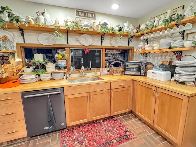 kitchen with dishwashing machine, sink, and butcher block countertops