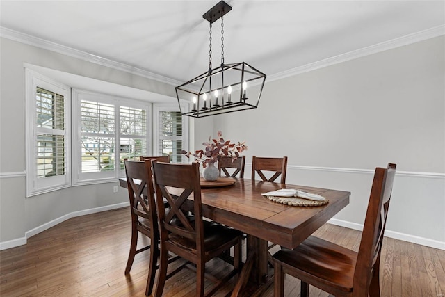 dining space featuring ornamental molding, wood finished floors, and baseboards