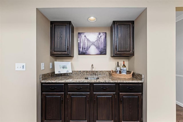 bar with wet bar, a sink, baseboards, and wood finished floors