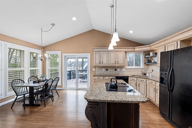 kitchen featuring light wood finished floors, lofted ceiling, cream cabinets, plenty of natural light, and black appliances