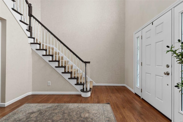 entryway featuring stairway, wood finished floors, a towering ceiling, and baseboards