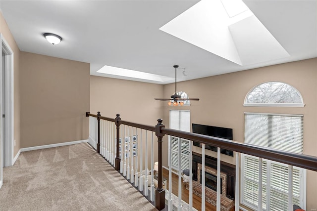 corridor featuring carpet floors, a skylight, and baseboards