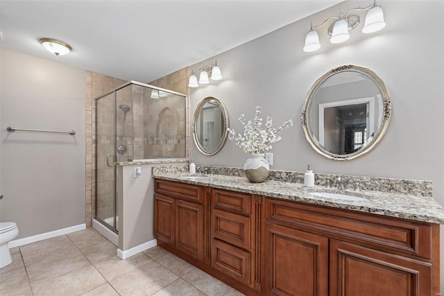 full bathroom with double vanity, toilet, a stall shower, a sink, and tile patterned flooring