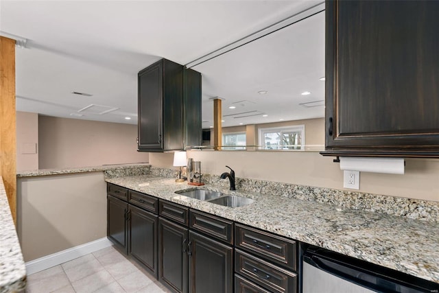 kitchen featuring light stone counters, light tile patterned floors, stainless steel dishwasher, a sink, and baseboards