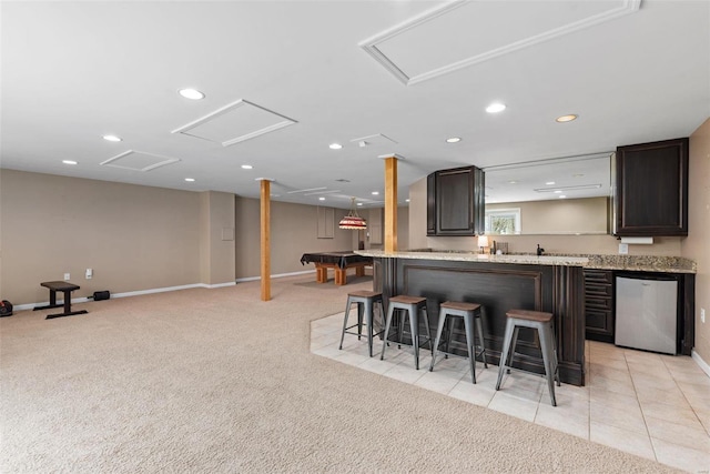 kitchen featuring dishwasher, recessed lighting, a kitchen bar, and light colored carpet