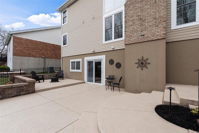 rear view of property featuring stucco siding, an outdoor fire pit, fence, and a patio