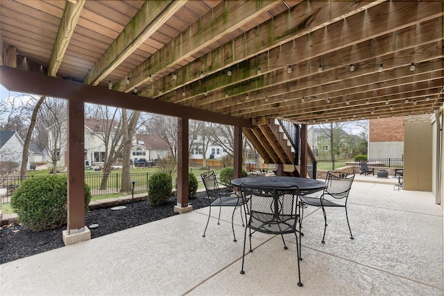 view of patio featuring stairway, outdoor dining area, fence, and a residential view