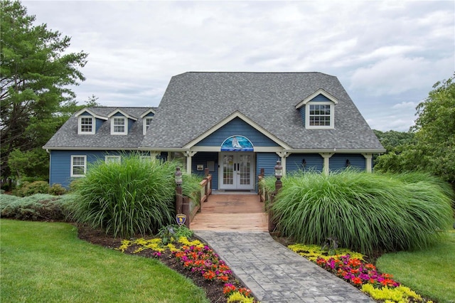 cape cod-style house with french doors, roof with shingles, and a front yard