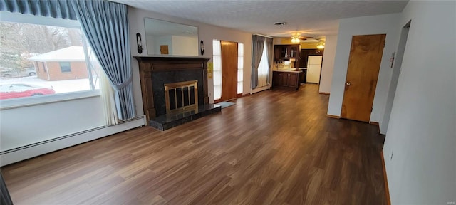 unfurnished living room with a fireplace, dark wood-style floors, a wealth of natural light, and a ceiling fan