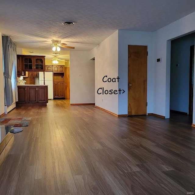 unfurnished living room featuring baseboards, a textured ceiling, ceiling fan, and dark wood finished floors