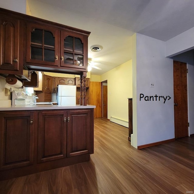 kitchen with dark wood-style floors, visible vents, a peninsula, freestanding refrigerator, and a baseboard heating unit