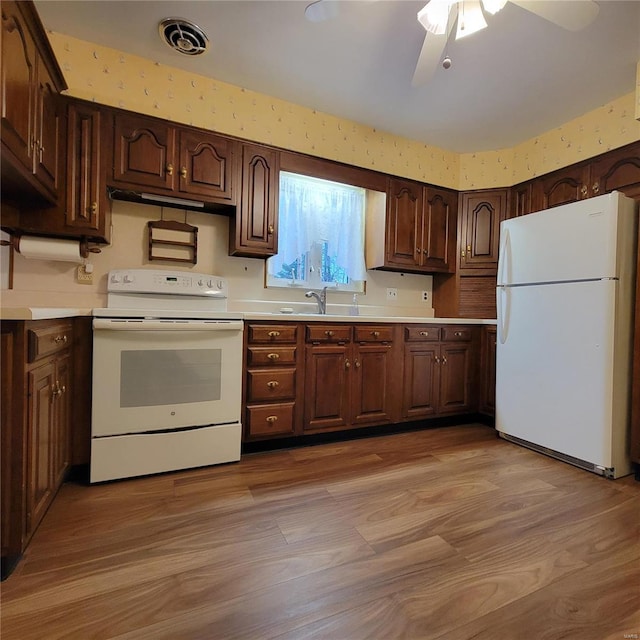 kitchen featuring visible vents, light wood-style flooring, a ceiling fan, white appliances, and light countertops