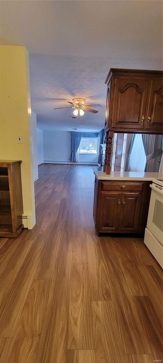 kitchen featuring white range with electric stovetop, dark wood finished floors, light countertops, and a ceiling fan