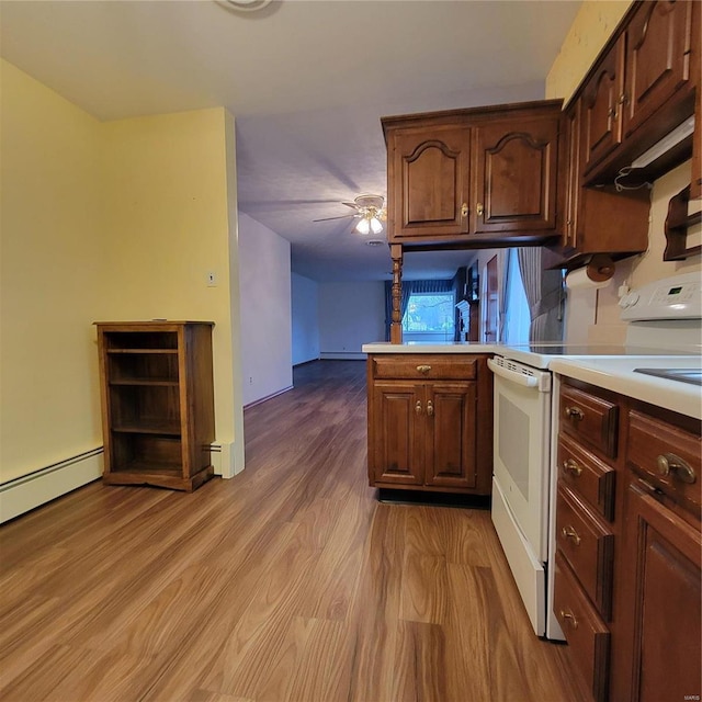 kitchen featuring a ceiling fan, light wood finished floors, a peninsula, electric range, and light countertops