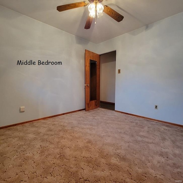 carpeted spare room with baseboards and a ceiling fan