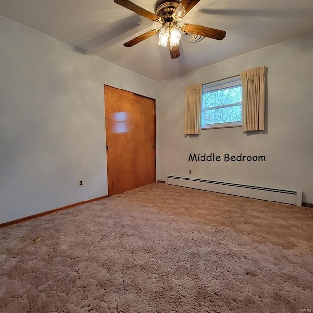 unfurnished bedroom with a baseboard heating unit, baseboards, carpet, a closet, and a ceiling fan