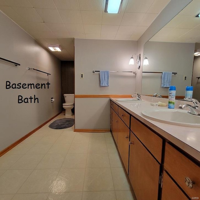 full bath featuring a sink, baseboards, toilet, and double vanity