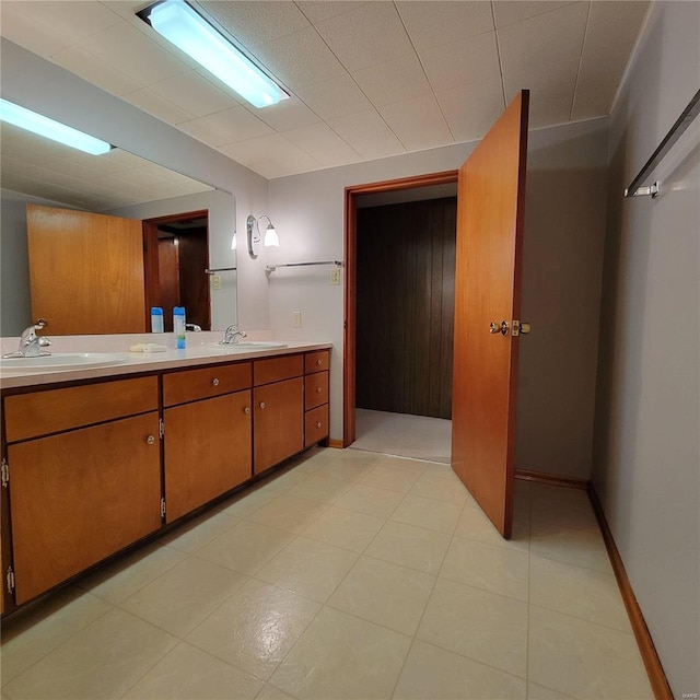 full bath with double vanity, baseboards, and a sink