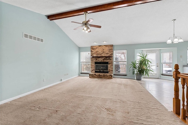 unfurnished living room featuring a textured ceiling, ceiling fan with notable chandelier, a fireplace, light carpet, and beam ceiling