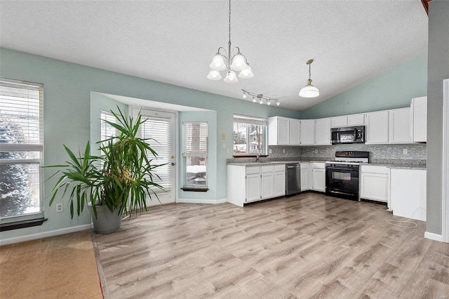 kitchen with appliances with stainless steel finishes, backsplash, light wood-type flooring, white cabinets, and hanging light fixtures