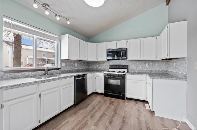 kitchen with sink, backsplash, vaulted ceiling, appliances with stainless steel finishes, and white cabinets