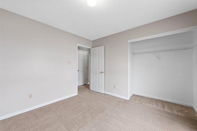 unfurnished bedroom with a closet, a textured ceiling, and light colored carpet