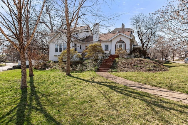 view of front facade featuring stucco siding, a chimney, and a front yard