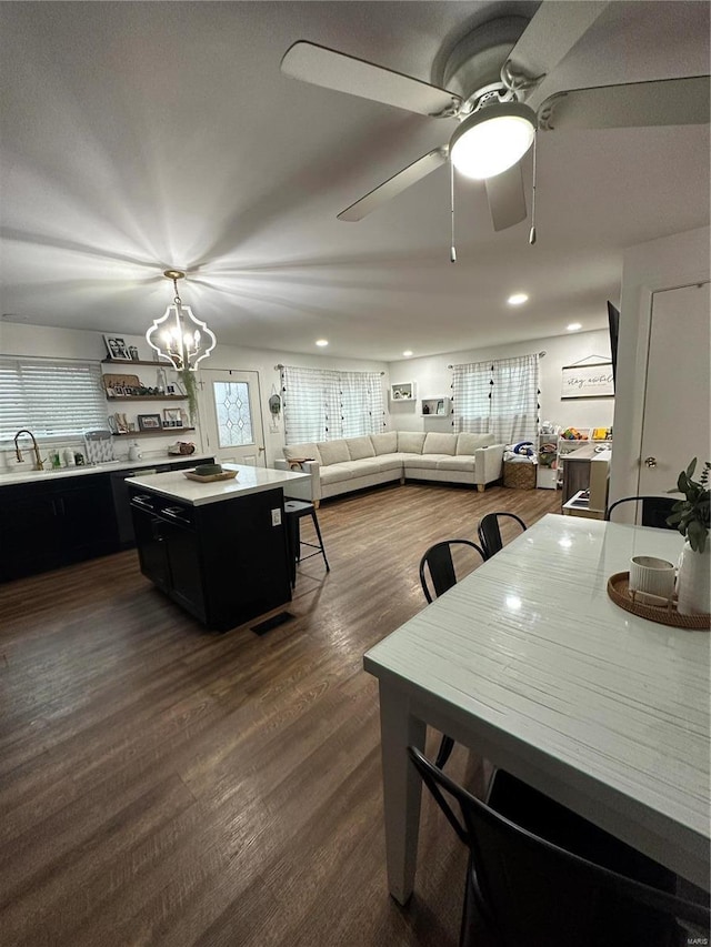 dining area with ceiling fan with notable chandelier, dark wood-type flooring, and sink