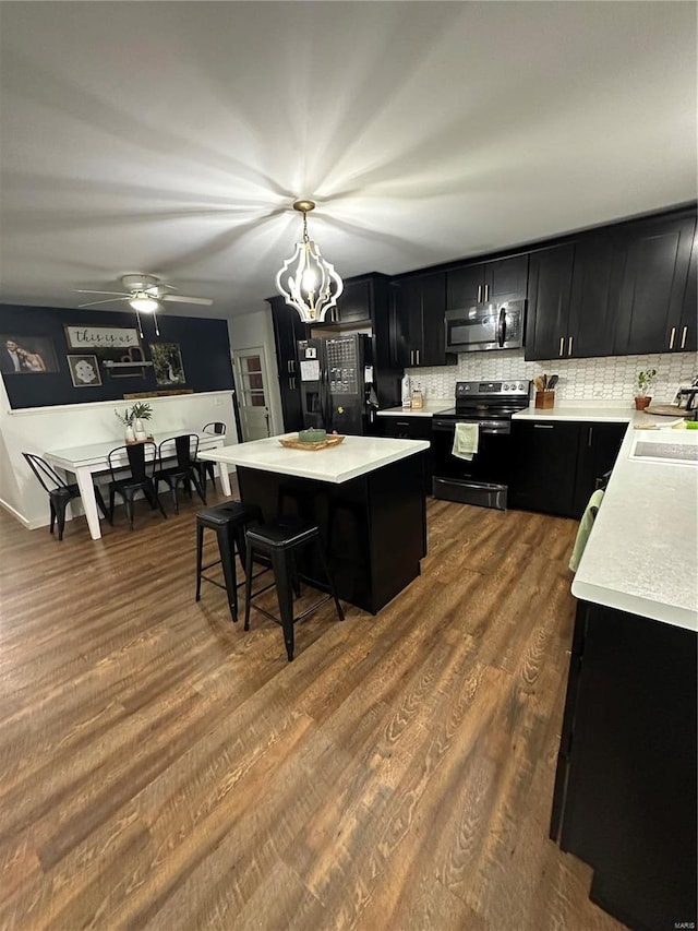 kitchen featuring a breakfast bar, hanging light fixtures, a kitchen island, hardwood / wood-style flooring, and black appliances