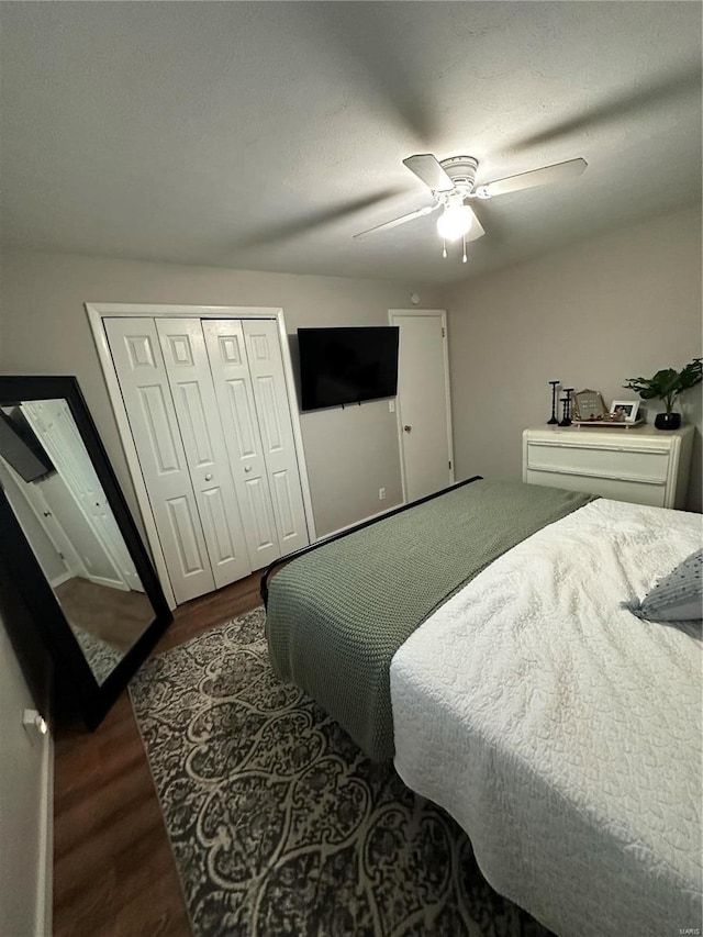 bedroom featuring ceiling fan, a textured ceiling, dark hardwood / wood-style flooring, and a closet