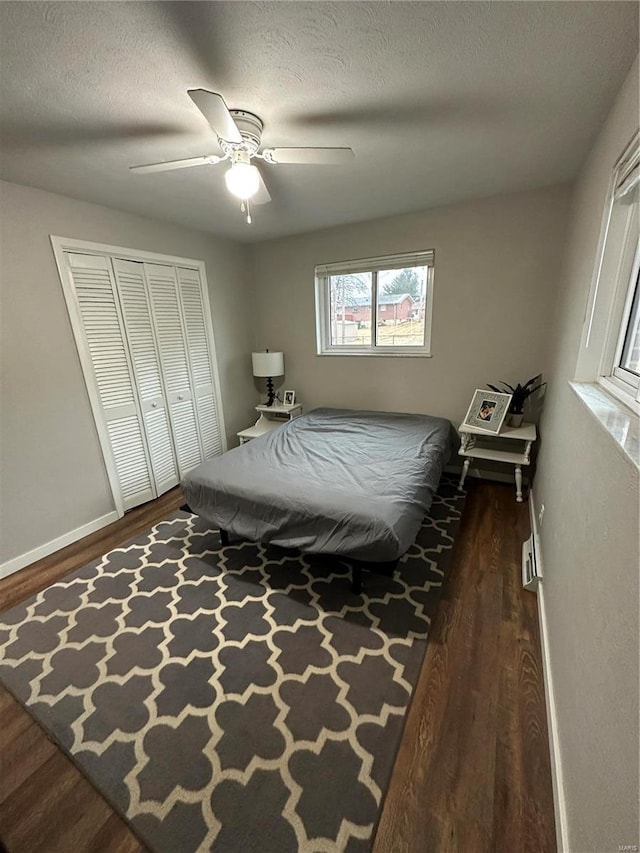 bedroom with ceiling fan, dark hardwood / wood-style floors, a closet, and a textured ceiling