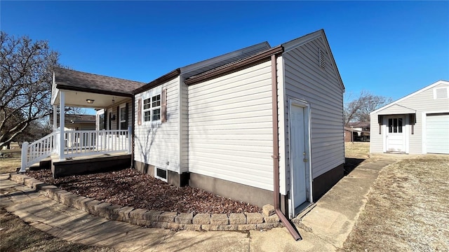 view of property exterior with a porch, a garage, and an outbuilding