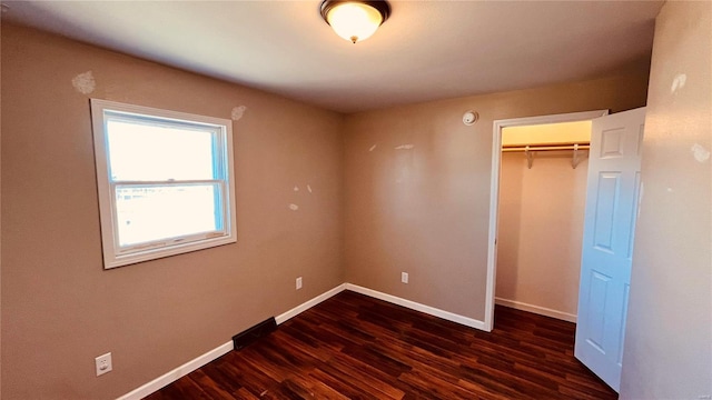 unfurnished bedroom featuring dark hardwood / wood-style flooring and a closet