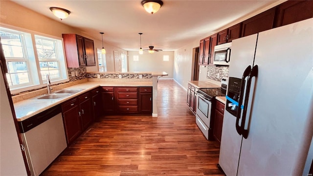 kitchen featuring sink, wood-type flooring, decorative light fixtures, kitchen peninsula, and stainless steel appliances