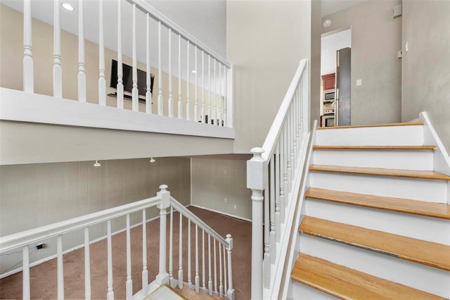 stairs with carpet flooring and a towering ceiling