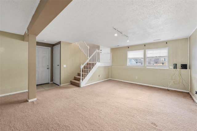 carpeted spare room featuring baseboards, stairway, and a textured ceiling