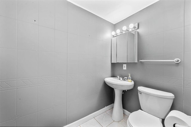 half bath with toilet, tile walls, and tile patterned floors