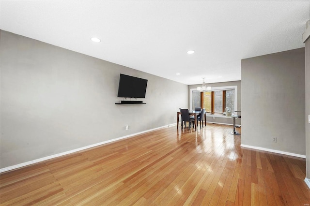 unfurnished living room featuring light wood-style floors, recessed lighting, a chandelier, and baseboards