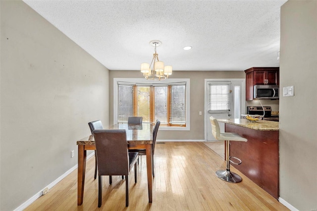 dining room with light wood-style flooring, baseboards, and a notable chandelier