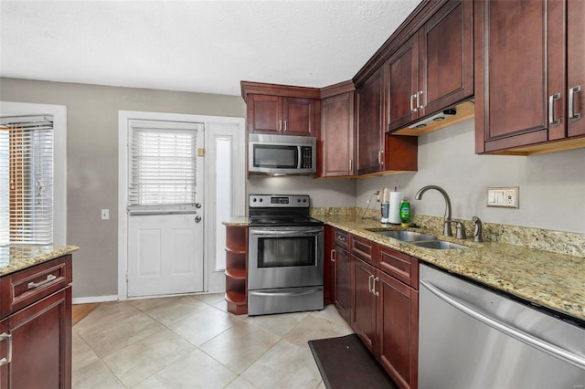 kitchen featuring light tile patterned floors, light stone counters, stainless steel appliances, a sink, and dark brown cabinets