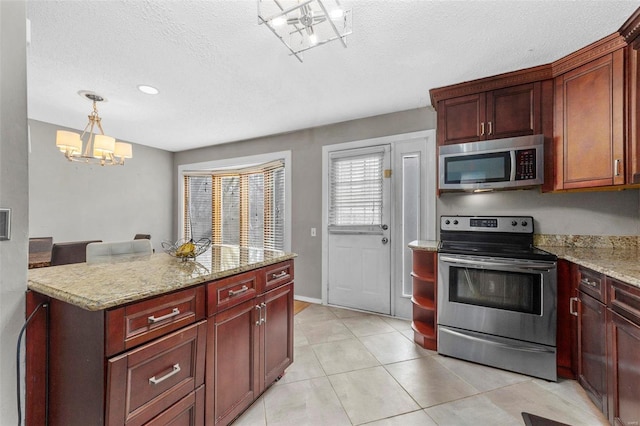 kitchen featuring a textured ceiling, stainless steel appliances, light stone counters, and a notable chandelier