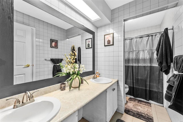 full bathroom featuring tile patterned flooring, a sink, and tile walls