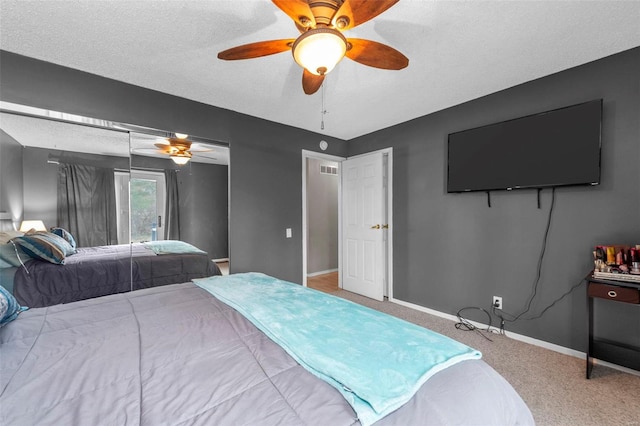 carpeted bedroom featuring a ceiling fan, visible vents, a textured ceiling, and baseboards