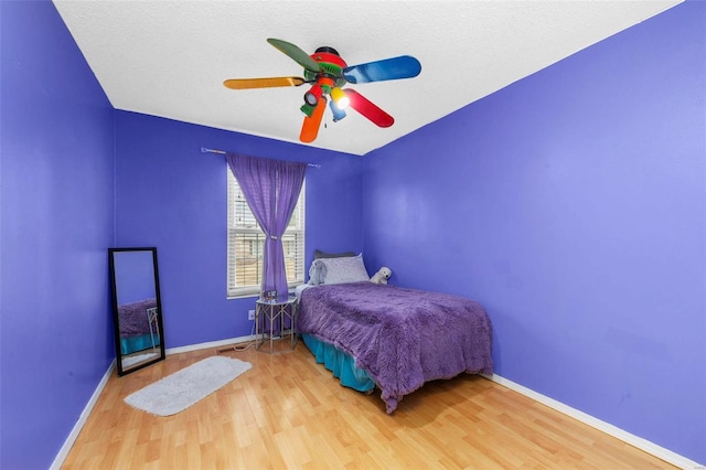 bedroom featuring ceiling fan, baseboards, and wood finished floors