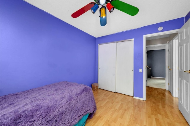 bedroom with attic access, baseboards, a ceiling fan, wood finished floors, and a closet