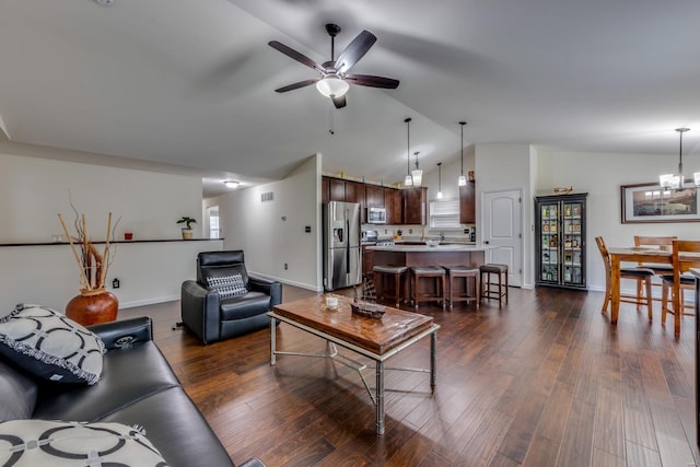 living room featuring lofted ceiling, ceiling fan with notable chandelier, and dark wood-type flooring