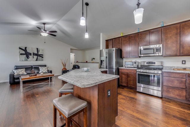 kitchen featuring a breakfast bar, decorative light fixtures, dark hardwood / wood-style flooring, a kitchen island, and stainless steel appliances