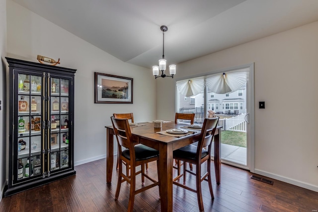 dining area featuring vaulted ceiling, dark hardwood / wood-style floors, and an inviting chandelier