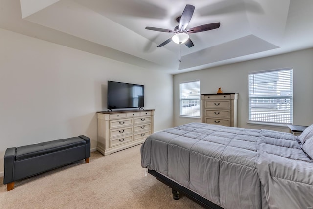 bedroom with light carpet, a tray ceiling, and ceiling fan